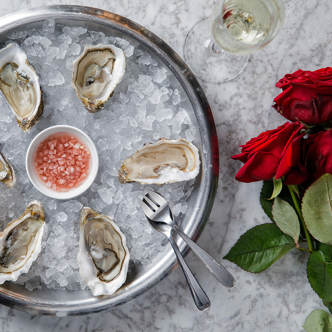A plate of oysters, accompanied by a rose