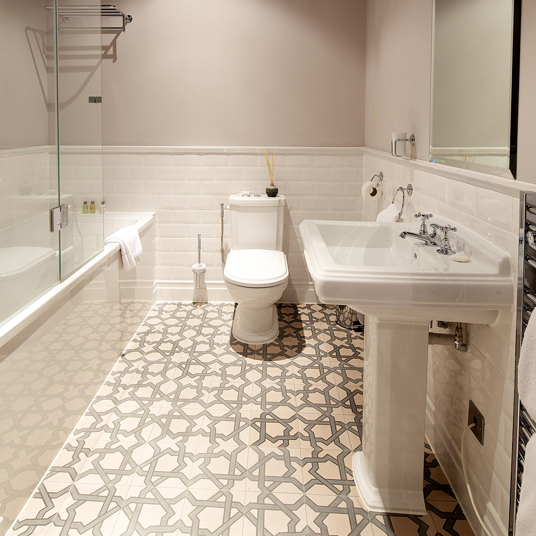 Large tiled bathroom with bath, loo, and pedestal sink