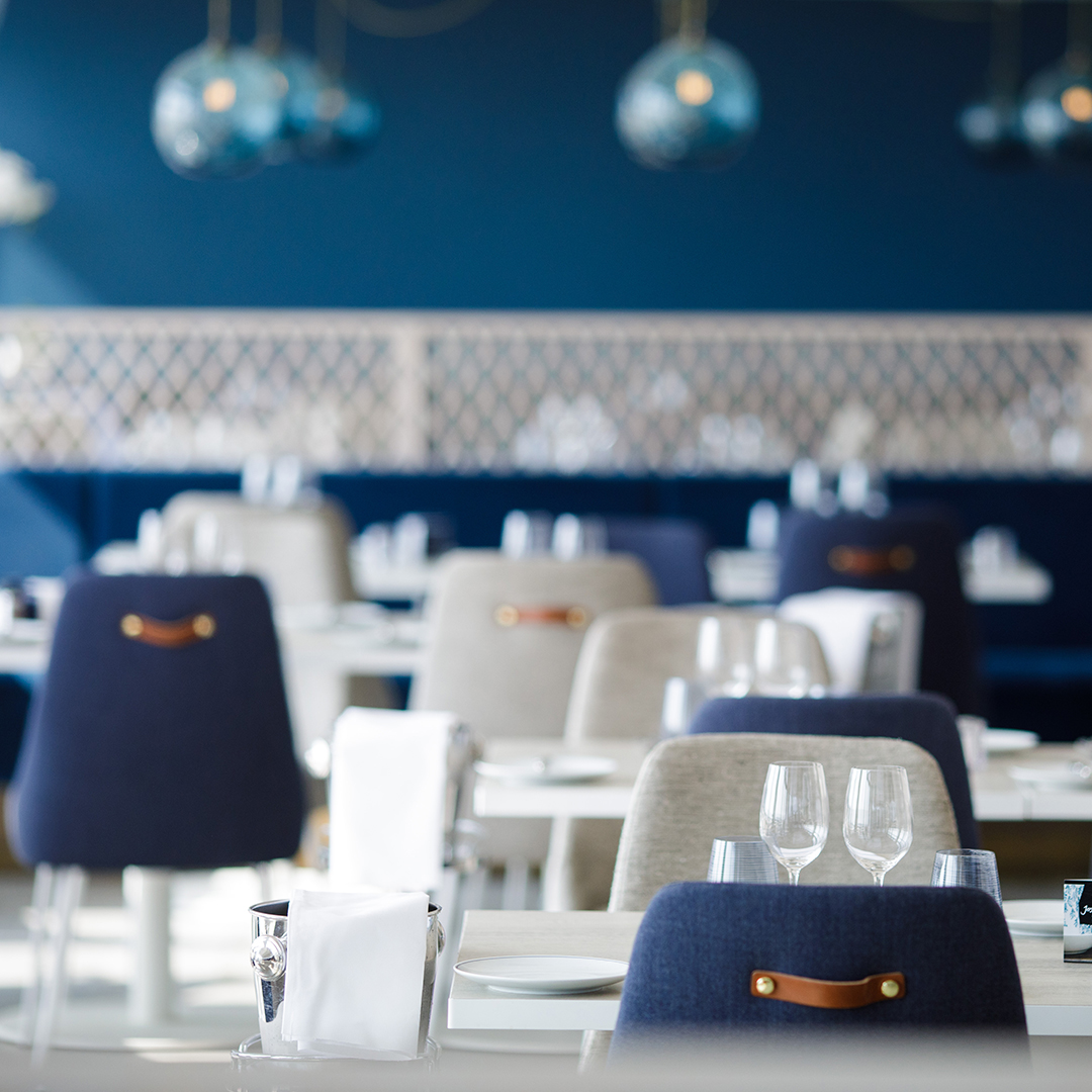 Chic blue and cream upholstered chairs in smart dining room with blue glass light fixtures