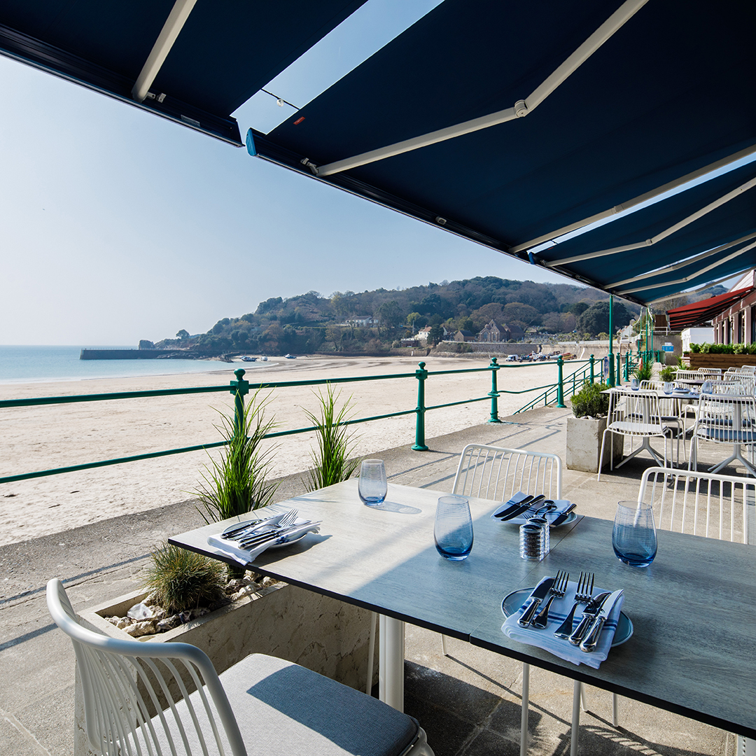 Terrace beside sandy beach with elegant tables and awning