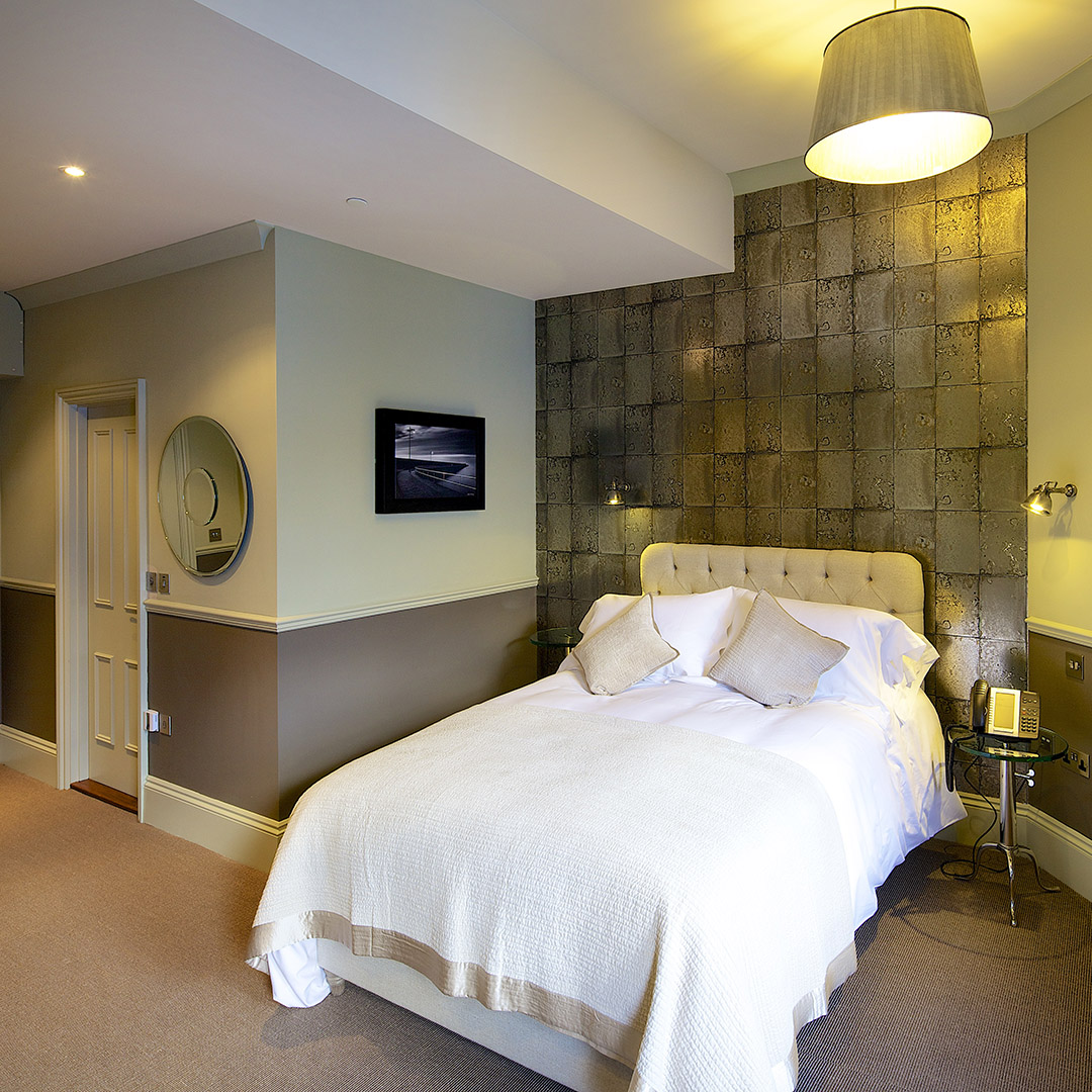 Spacious room with green accent wall, double bed and luxury bedding
